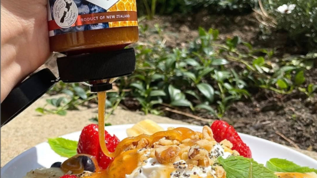 Manuka Lab honey being drizzled over a fresh fruit and yogurt breakfast bowl outdoors.